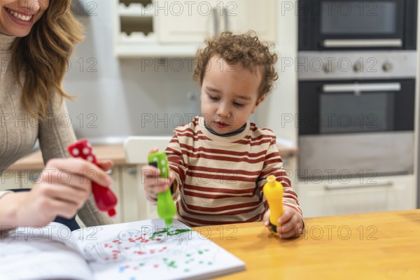 Mother and young child engaging in fun coloring activities at a kitchen island, using colorful dot markers in a workbook, fostering creativity and learning at home