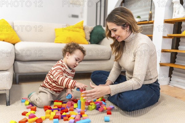 Young mother smiling, sitting on the floor with her toddler, actively engaging in playtime and learning while constructing with various colorful wooden blocks in a modern living room at home