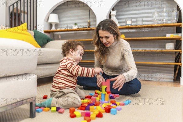 Mother and son bonding while happily playing with colorful wooden blocks on the living room floor, building and learning together during a fun family activity at home