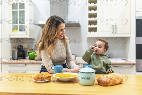 Mother smiles at her young child across the kitchen counter during a bright, cozy breakfast, sharing a warm, candid moment of nurturing, joy, and everyday togetherness at home
