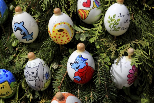 Detail, eggs painted by children, captain bluebear, Easter fountain in Heiligenstadt, Franconian Switzerland, Bamberg district, Upper Franconia, Bavaria, Germany, creative and brightly painted Easter eggs on green branches that represent various cheerful motifs
