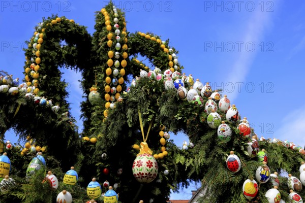 Easter fountain in Heiligenstadt, Franconian Switzerland, Bamberg district, Upper Franconia, Bavaria, Germany, An artfully decorated Easter fountain with colorful eggs against a bright blue sky