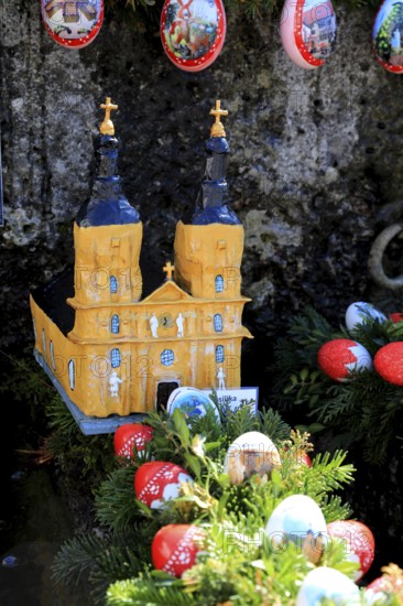 The monastery church Vierzehnheiligen built as a model in an Easter fountain, Franconian Switzerland, in Kleingesee, Gößweinstein market in the district of Forchheim, Upper Franconia, Bavaria, Germany, church model surrounded by decorated eggs and green foliage, Christmas atmosphere