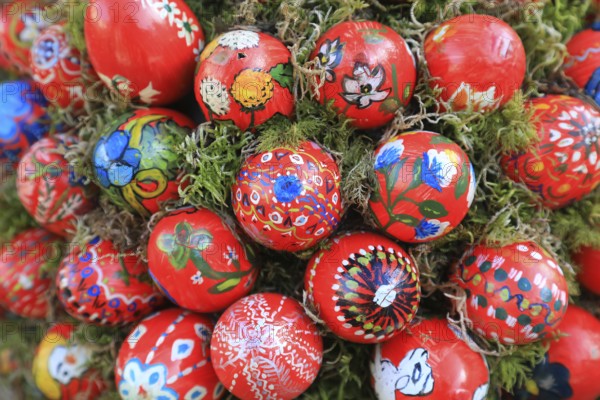 Detail of an Easter fountain in Franconian colors red and white, Franconian Switzerland, in Kleingesee, Gößweinstein market in the district of Forchheim, Upper Franconia, Bavaria, Germany, artfully painted red Easter eggs with natural motifs on moss, festive craftsmanship