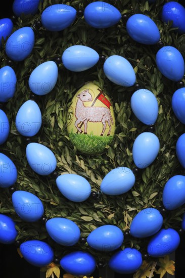 Easter fountain in Tiefenpölz, Markt Heiligenstadt, Franconian Switzerland, Bamberg district, Upper Franconia, Bavaria, Germany, decorated Easter egg with a lamb surrounded by blue eggs and leaves