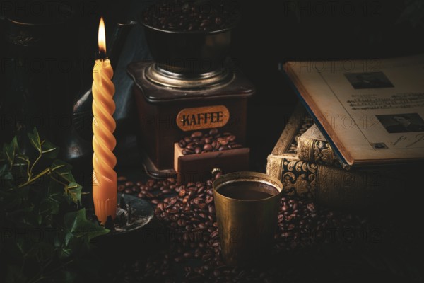 Cosy scene with old coffee grinder, steaming coffee and burning candle in a dark atmosphere