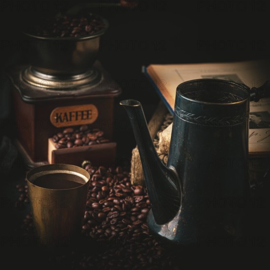 Coffee grinder, antique pot and mug with coffee surrounded by coffee beans and old books