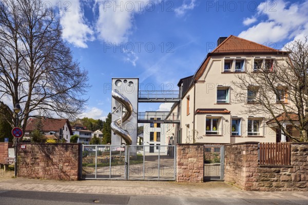 Catholic kindergarten St. Michael, slide, play equipment, commercial building, modern architecture, sandstone wall, wooden fence, metal gate, bare winter trees, blue sky, cumulus clouds, cirrus clouds, Untere Forststraße, Waldaschaff, Lower Franconia, Aschaffenburg district, Bavaria, Germany