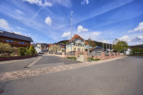 Town hall, maypole, flagpoles, roads, commercial buildings, residential buildings, single-family house, apartment buildings, general development, housing development, hills, coniferous forest, blue sky, cumulus clouds, confluence Hessenthälchenweg in Am Mühlbach, Waldaschaff, Lower Franconia, Aschaffenburg district, Bavaria, Germany