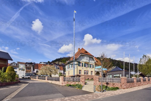 Town hall, maypole, sandstone wall, wooden fence, roads, commercial buildings, residential buildings, single-family house, apartment buildings, general development, housing development, hills, coniferous forest, blue sky, cumulus clouds, confluence Hessenthälchenweg in Am Mühlbach, Waldaschaff, Lower Franconia, Aschaffenburg district, Bavaria, Germany