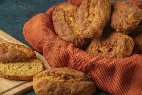 Fresh potato rolls in a basket with orange cloth, one cut open
