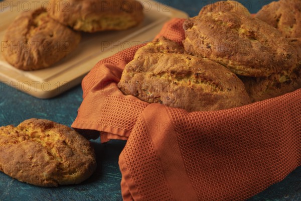 Fresh potato rolls in a basket with orange cloth, some presented on a wooden board
