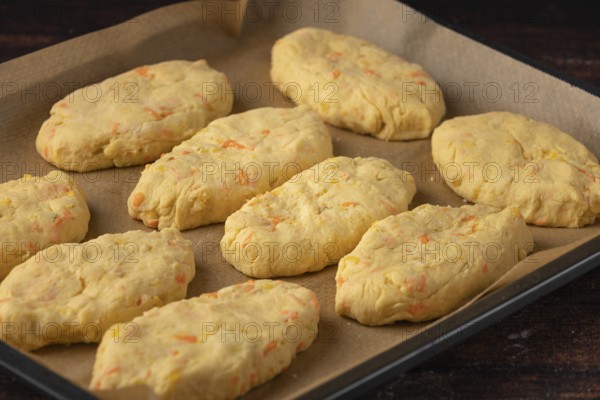 Unbaked potato rolls on a baking tray lined with baking paper