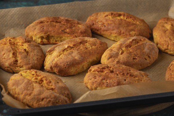 Freshly baked potato rolls on a baking tray lined with baking paper