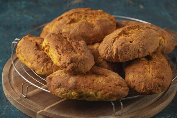 Stacks of freshly baked potato rolls with golden brown crust on a wire rack