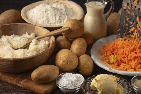 Grated cheese and carrots next to potatoes and flour