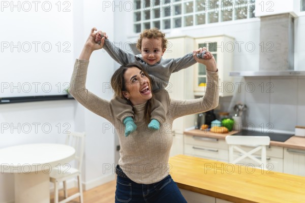 Mother enjoying playtime with her son on a piggyback ride at home, sharing laughter and bonding during a joyful childhood moment in a bright kichen setting