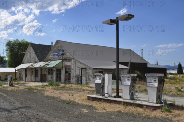 Abandoned gas station with old gas pumps in front of a rural shop, Unity, Oregon, USA