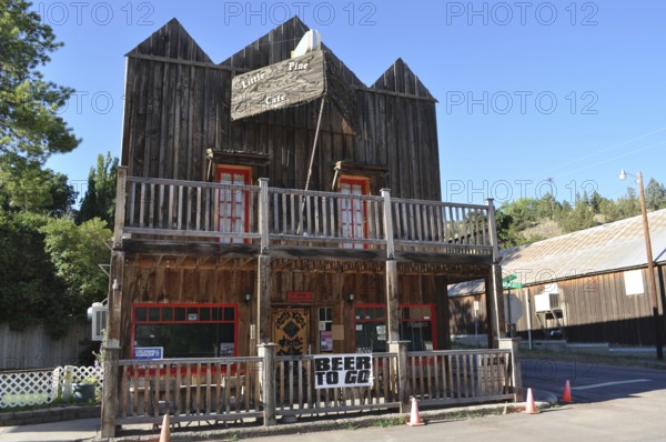Two-story wooden building with porch and 'beer to go' sign under blue sky, Mitchell, Oregon, USA