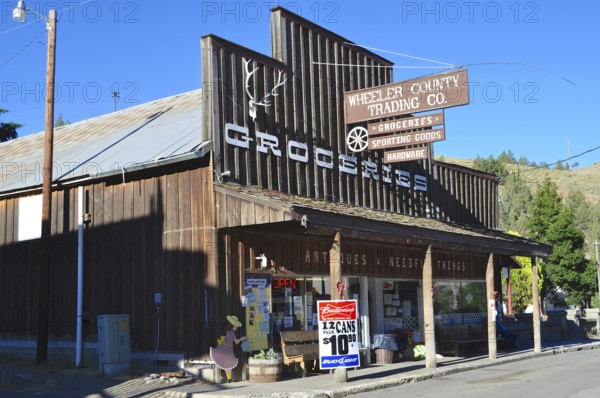 A shop with a wooden façade and several signs identifying the shop as a retail space, Mitchell, Oregon, USA