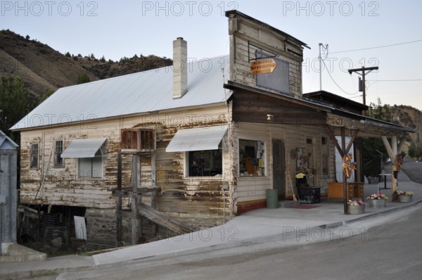 An old, weathered timber house on a hillside with a covered porch and chimney, Mitchell, Oregon, USA