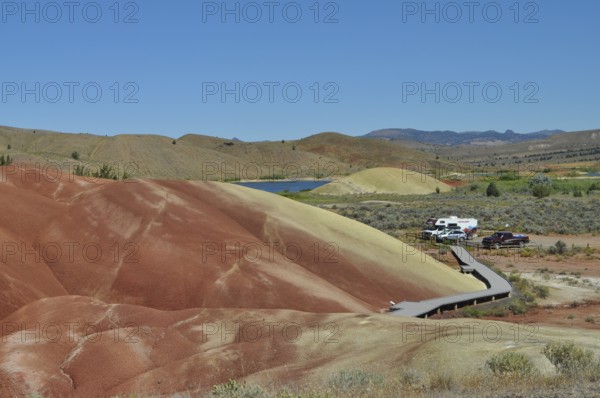 Parking lot and wooden path surrounded by colored hills, John Day Fossil Beds National Monument, Painted Hills Unit, Oregon, USA