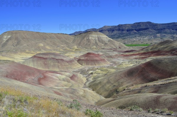 Wide landscape with multicolor hills and blue sky, John Day Fossil Beds National Monument, Painted Hills Unit, Oregon, USA