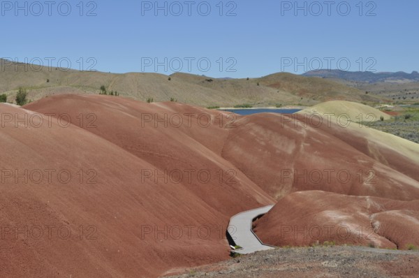 Winding wooden trail through red mounds, John Day Fossil Beds National Monument, Painted Hills Unit, Oregon, USA