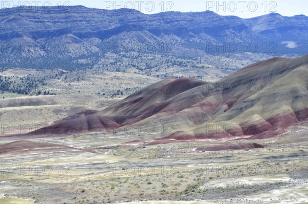 Wide landscape with colorful hills and red stripes in the foreground, John Day Fossil Beds National Monument, Painted Hills Unit, Oregon, USA
