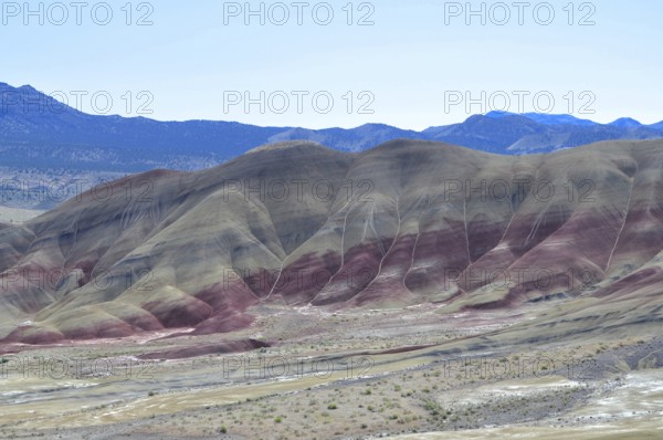 Colourful hills with red stripes under clear skies. Impression of an eroded geological formation, John Day Fossil Beds National Monument, Painted Hills Unit, Oregon, USA