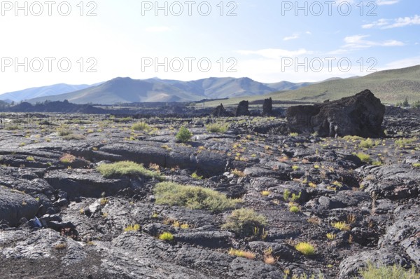 Wide lava plate with scattered vegetation under blue sky, Craters of the Moon National Monument, Idaho, USA