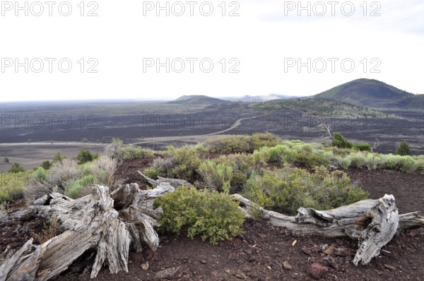 Wide, rocky lava rock plain with grasses and distant hills, Craters of the Moon National Monument, Idaho, USA
