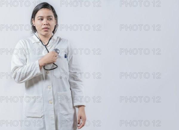 Asian Female Doctor Listening to Her Own Heartbeat with Stethoscope isolated. Young female doctor hearing Her Own Heartbeat with Stethoscope