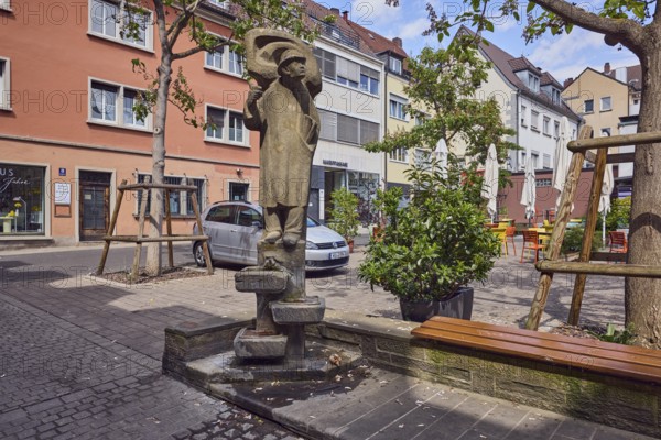 Lauscherbrunnen, stone fountain, sculpture of a person, sculptor Oskar Müller, public art, residential building, parking boxes with car, outdoor area of a restaurant, bench, trees, blue sky, cumulus clouds, Langgasse alleyway, Schenkhof square, Würzburg, Lower Franconia, district-free city, Bavaria, Germany