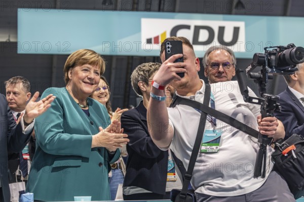 38th Federal Party Congress of the CDU of Germany in Stuttgart. Applause for Chancellor Friedrich Merz's speech. Selfie of a social media activist with former German Chancellor Angela Merkel. Bodyguards were not amused. facial expressions. Stuttgart, Baden-Württemberg, Germany