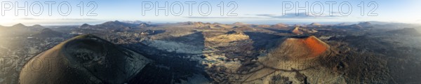 Picturesque volcanic landscape with volcanic craters and lava fields in morning light, Montaña Negra volcano, Caldera Colorada and Volcán de Las Nueces, Los Volcanes Natural Park, aerial view, Lanzarote, Canary Islands, Spain