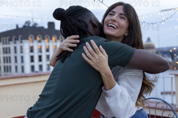 Two friends embrace joyfully on a rooftop, celebrating a party full of happiness and connection The evening lights add a festive atmosphere to the scene