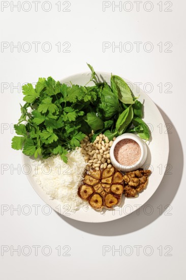 Top view of a plate with fresh ingredients for making Italian pesto gnocchi, featuring potatoes, parmesan cheese, walnuts, basil, parsley leaves, and a bowl of sauce