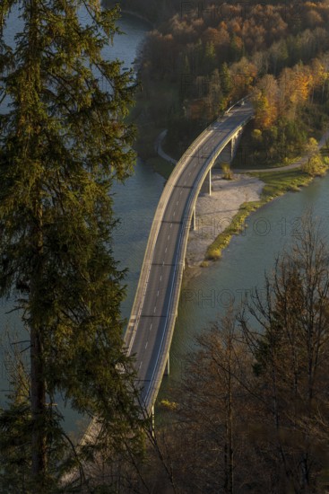 A picturesque Faller-Klamm Bridge gracefully arches over a serene river surrounded by vibrant autumn foliage in the Bavarian Alps, capturing the essence of nature and engineering