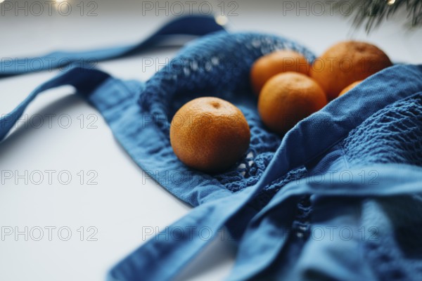 Close-up view of ripe tangerines neatly tucked inside a vibrant blue string bag, set against a soft, blurred background with subtle lighting