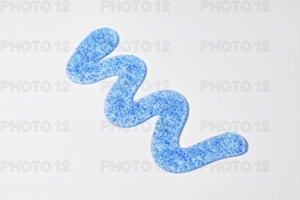 A blue face scrub with micro-exfoliating particles is arranged in a wave pattern on a white surface It highlights the product's vibrant color and texture, perfect for skincare themes