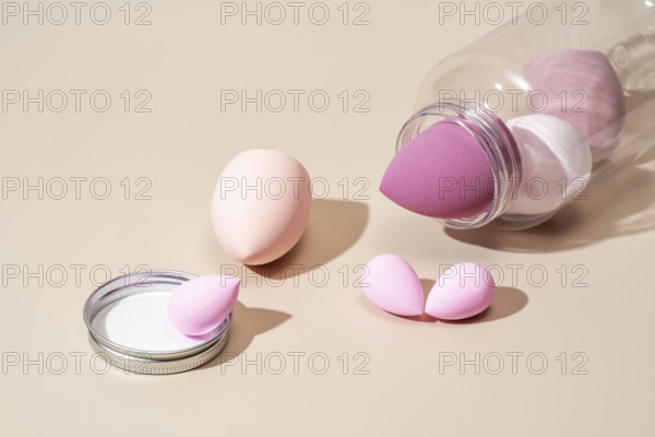 A collection of pink and beige cosmetic sponges arranged on a neutral beige background, ideal for makeup application The sponges add a soft touch to beauty routines