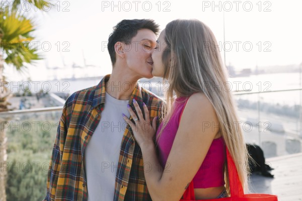 A happy lesbian couple shares a moment of love outdoors while kissing, celebrating diversity and pride. This image conveys love, inclusion and equality within the LGBTQIA+ community
