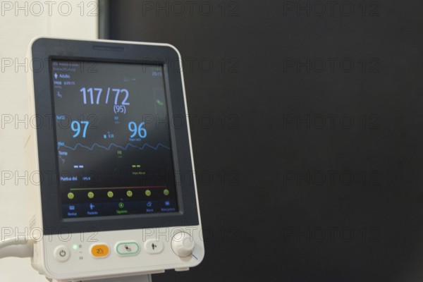 A mature woman is being monitored for vital signs like heart rate and blood pressure in a hospital setting, using a portable medical monitor