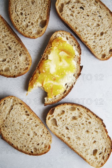 Top view of freshly sliced homemade sourdough bread topped with butter and jam, melted and drizzled