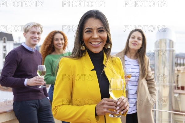 A group of cheerful friends enjoying a casual gathering on a rooftop, holding glasses of wine The stylish setting, smiles, and urban backdrop create a warm and lively atmosphere