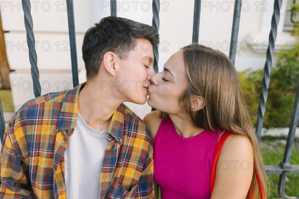 A happy lesbian couple shares a tender kiss while seated together, embracing love and affection. This image captures the essence of LGBTQIA+ pride and relationship equality