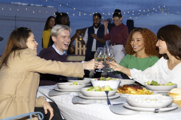 A group of friends enjoys a vibrant rooftop dinner party under string lights They share laughter and clink glasses over a beautifully set table, celebrating togetherness and joy
