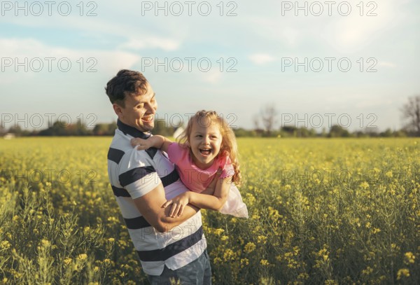 A young father and his little daughter play happily in nature in the summer. Happy parenting and childhood