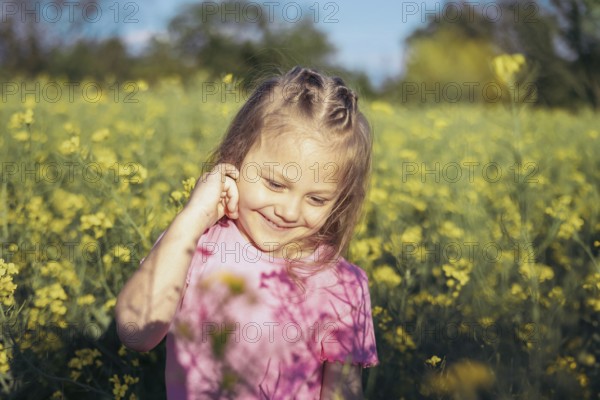 A little girl in a pink outfit smiles as she admires the flowers around her Her innocence and wonder capture the beauty of childhood in a peaceful countryside setting
